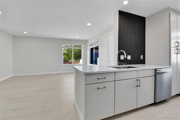 a kitchen with white cabinets and sink