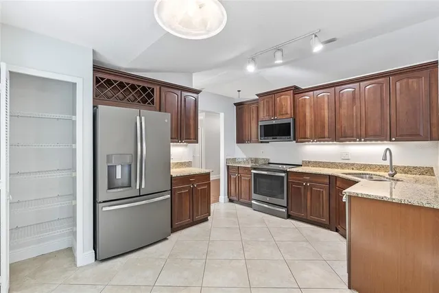 a large kitchen with granite countertop stainless steel appliances and wooden cabinets