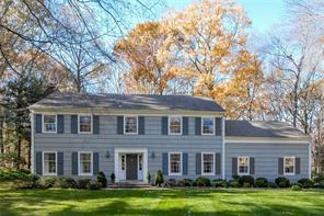 front view of a brick house next to a yard with large trees