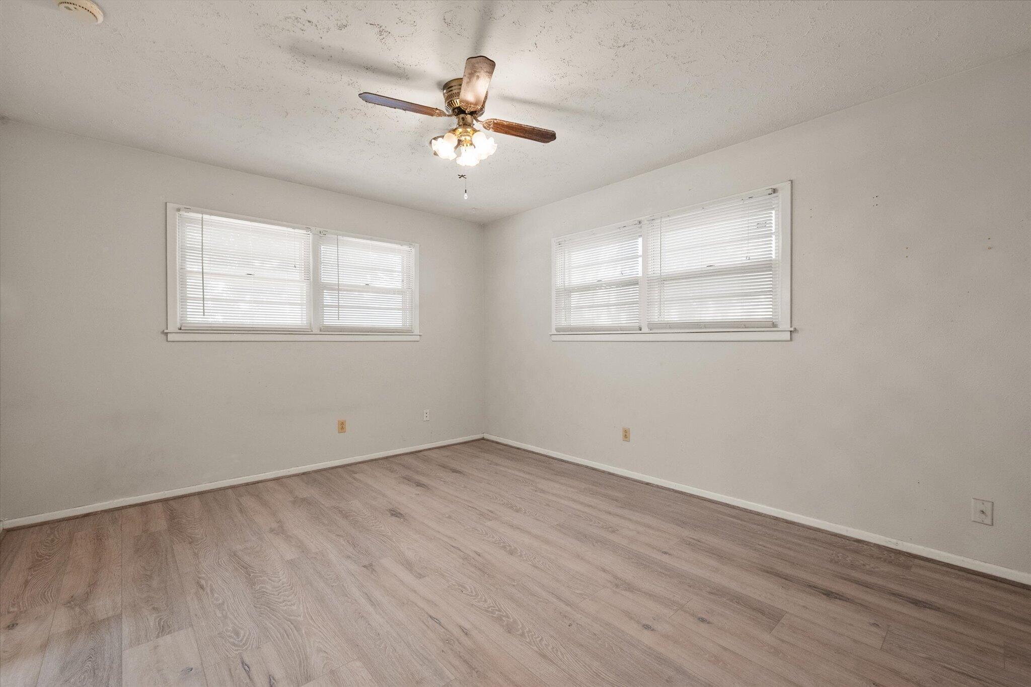 4604 27th Street Lubbock, TX 79410 - Photo 13 of 36 an empty room with wooden floor chandelier fan and windows