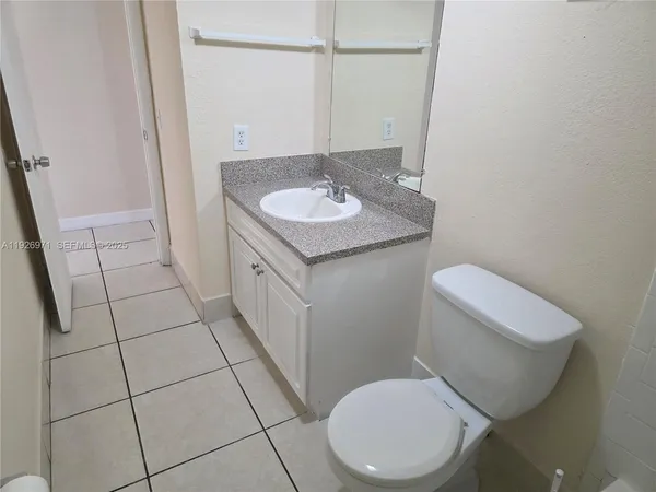 a bathroom with a granite countertop toilet sink and mirror