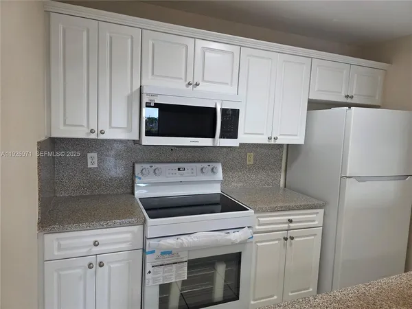 a kitchen with appliances a microwave and cabinets