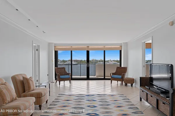 a living room with furniture floor to ceiling window and a flat screen tv