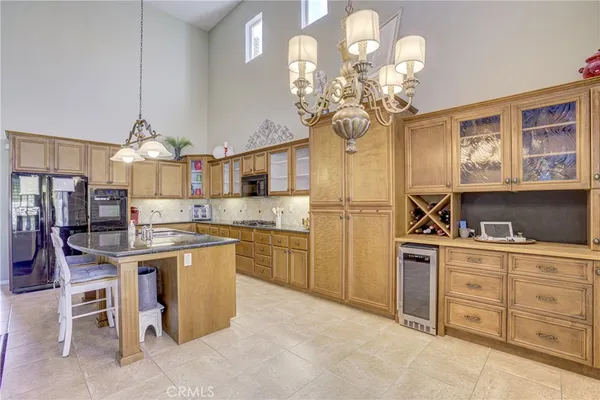 a kitchen with stainless steel appliances granite countertop a sink a stove oven a refrigerator cabinets and chairs