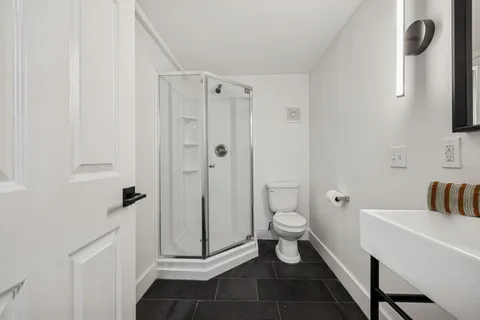 a bathroom with a sink a toilet a mirror and shower