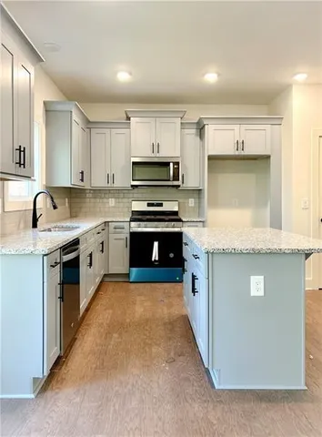 a kitchen with stainless steel appliances granite countertop a stove top oven a sink and a refrigerator