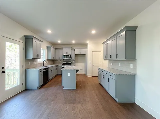 a large kitchen with granite countertop a large counter top space a sink stainless steel appliances and cabinets