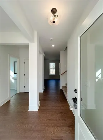 a view of a hallway with wooden floor and a bathroom