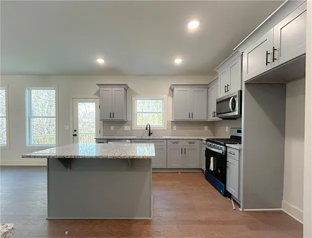 a kitchen with stainless steel appliances granite countertop a sink stove and refrigerator