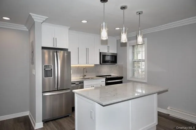 a kitchen with stainless steel appliances a refrigerator a sink a stove a microwave and wooden floor