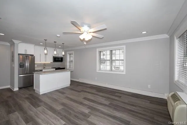 a kitchen with stainless steel appliances kitchen island wooden floor and window