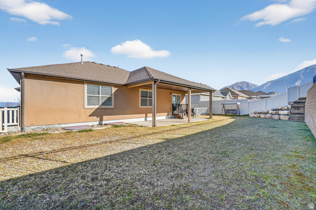 141 Wolverine Creek Elk Ridge, UT 84651 - Photo 34 of 47 Rear view of house with a fenced backyard, a patio area, stucco siding, roof with shingles, and a mountain view