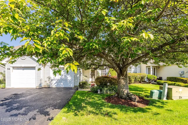 a front view of a house with a yard and tree s