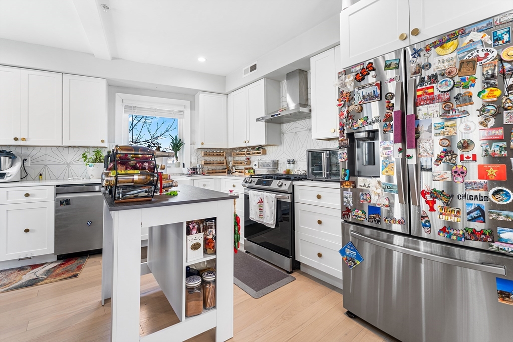 108 Maywood Street, Unit 2 Boston, MA 02119 - Photo 4 of 14 a kitchen with stainless steel appliances and white cabinets