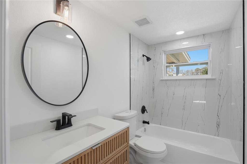 5543 Quist Drive Port Richey, FL 34668 - Photo 13 of 29 a bathroom with a sink a toilet and a mirror