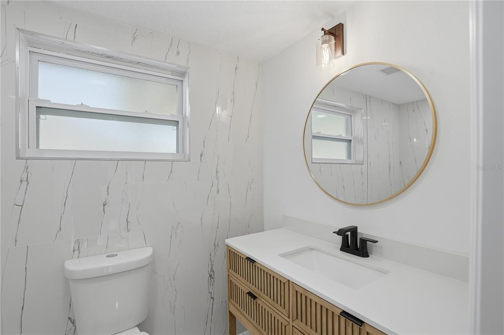 5543 Quist Drive Port Richey, FL 34668 - Photo 14 of 29 a bathroom with a sink a toilet and a mirror