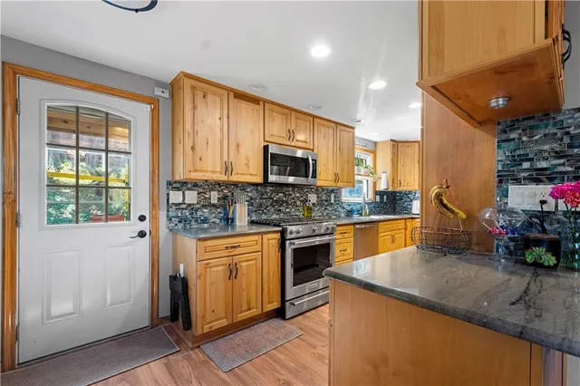 a kitchen with stainless steel appliances granite countertop a sink a stove and a refrigerator