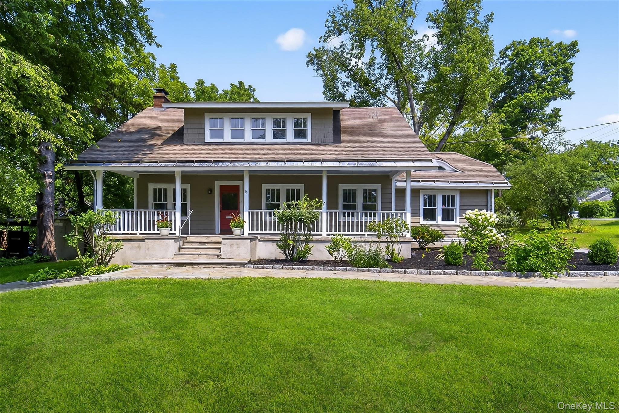 View of front of home featuring a front yard, a shingled roof, a chimney, and a porch