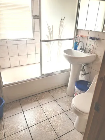 a bathroom with a sink a mirror and a bathtub next to a window