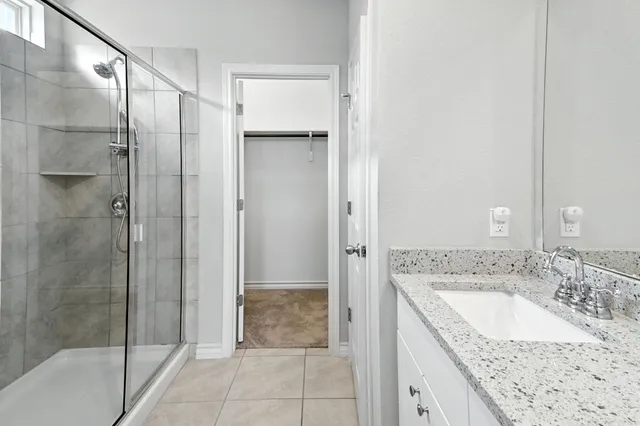 a bathroom with a granite countertop sink a mirror and shower