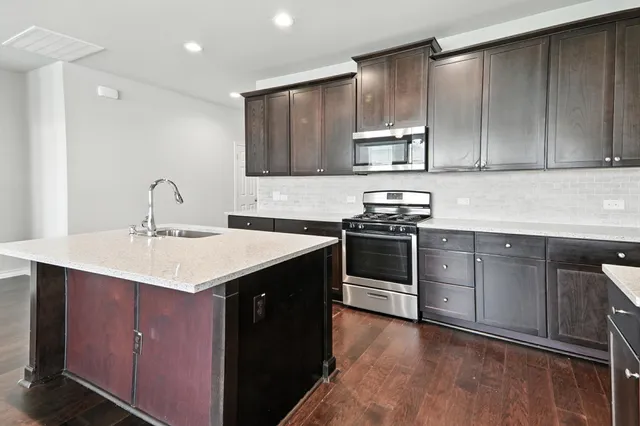 a kitchen with kitchen island granite countertop stainless steel appliances a sink stove top oven and cabinets