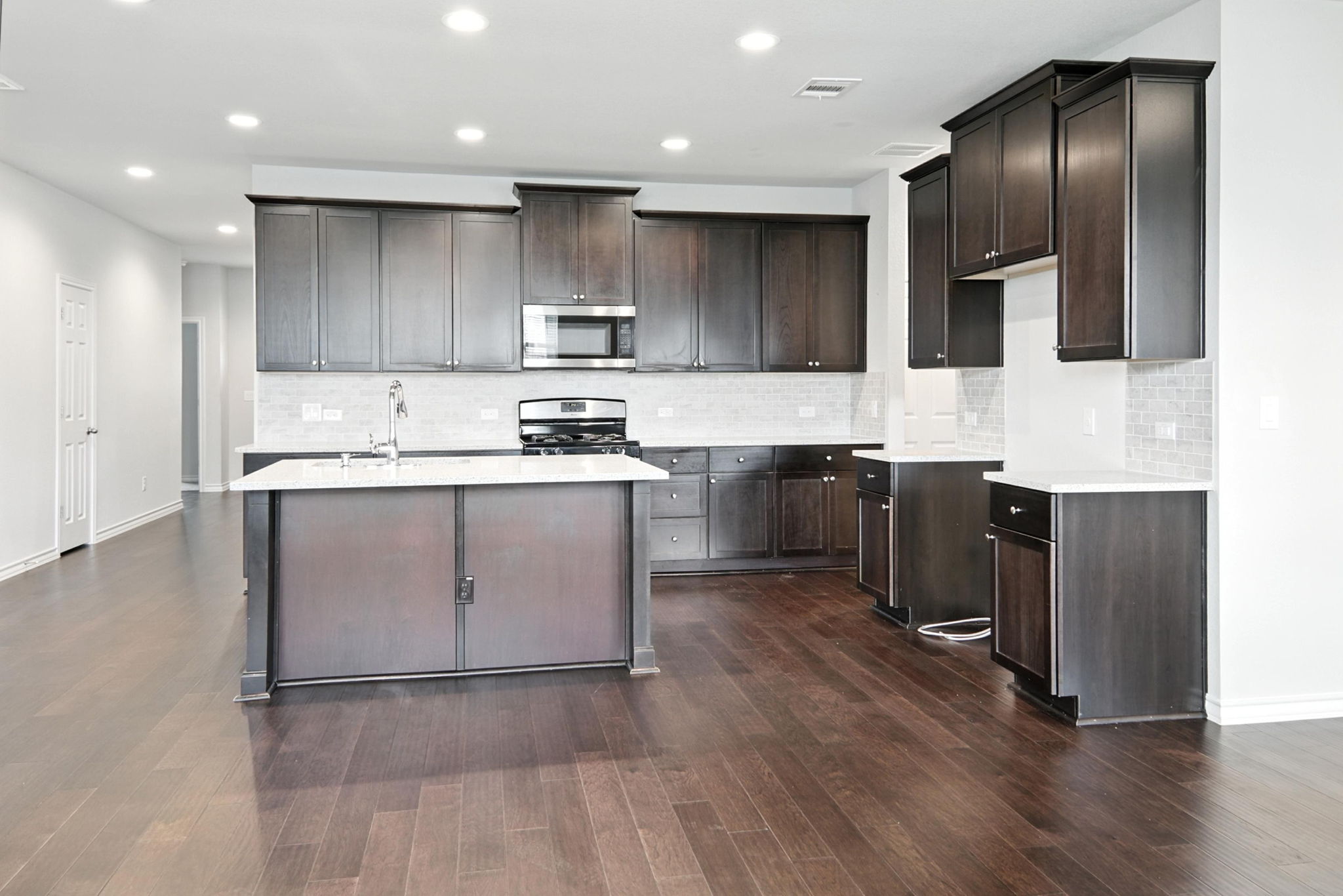 341 Coba Street Leander, TX 78641 - Photo 19 of 28 Kitchen with stainless steel appliances, dark wood-style floors, dark brown cabinets, decorative backsplash, and recessed lighting