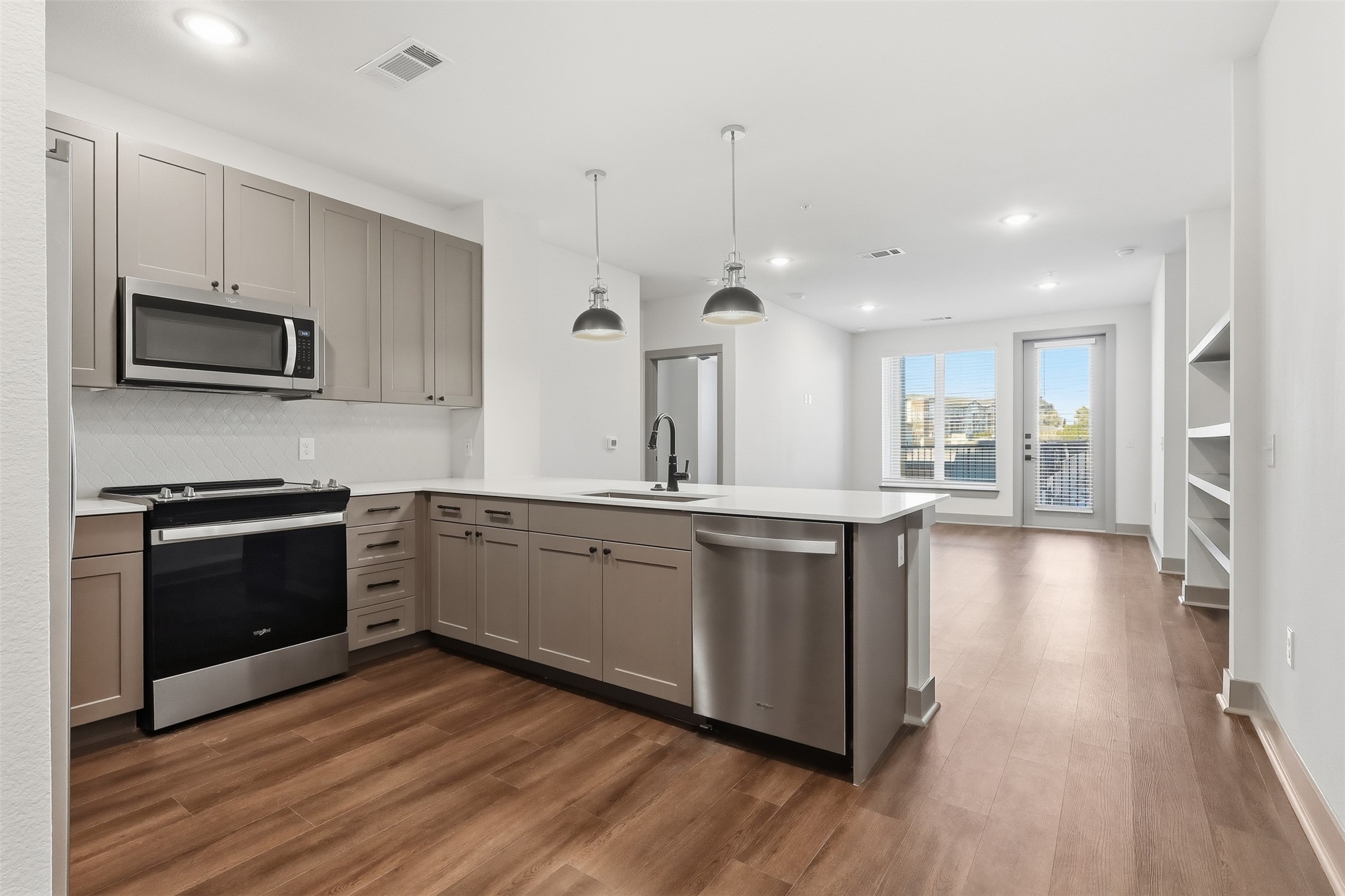 a large kitchen with stainless steel appliances and wooden floor