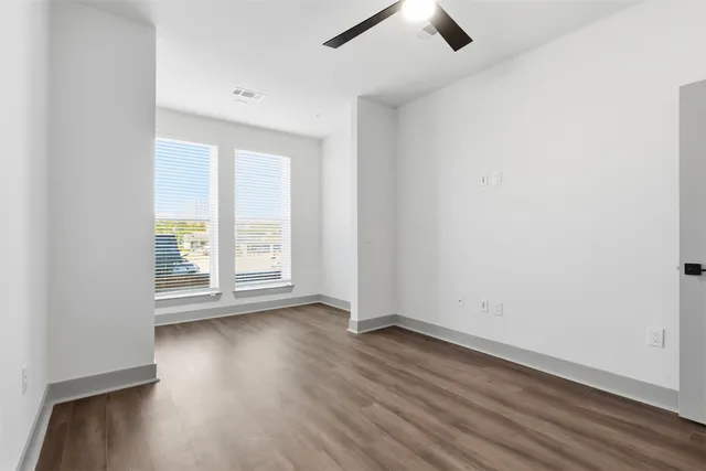 an empty room with wooden floor and windows