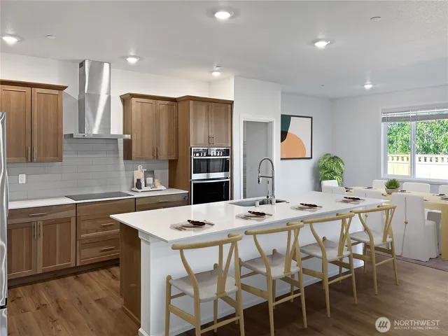 a kitchen with stainless steel appliances a table chairs refrigerator and cabinets