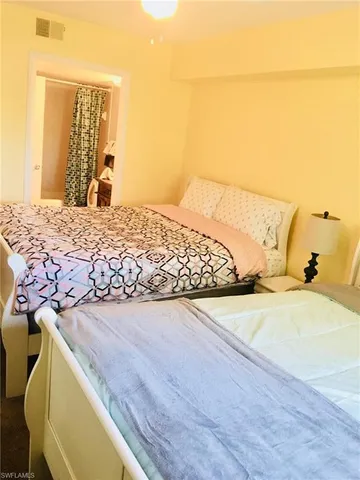 a bedroom with a bed and dresser with wooden floor