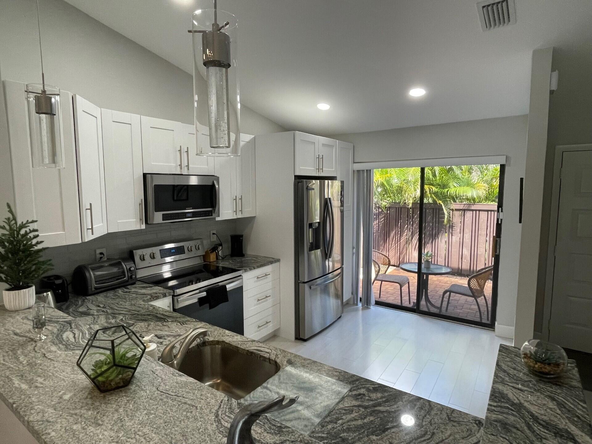 8471 Boca Glades Boulevard East Boca Raton, FL 33434 - Photo 12 of 29 a kitchen with stainless steel appliances granite countertop a sink a stove and a refrigerator
