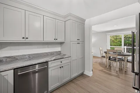 a kitchen with stainless steel appliances granite countertop a stove a sink and white cabinets with wooden floor