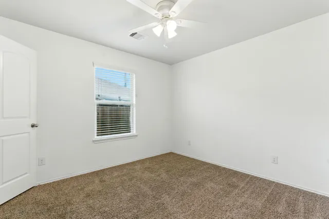 an empty room with a window and a fan