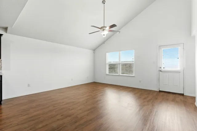 a view of an empty room with wooden floor and a window