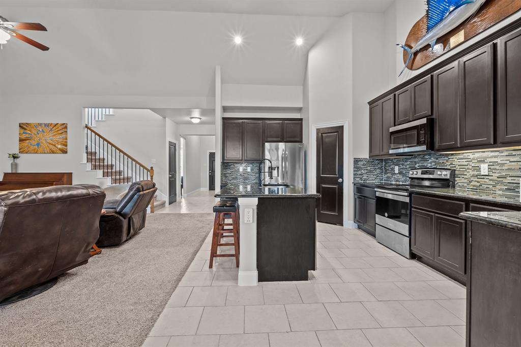 220 Flower Ridge Drive Fort Worth, TX 76108 - Photo 16 of 34 a kitchen with stainless steel appliances kitchen island granite countertop a refrigerator a stove and a sink with wooden cabinets
