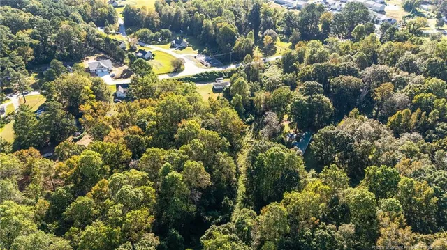 an aerial view of residential house with parking space and covered with trees