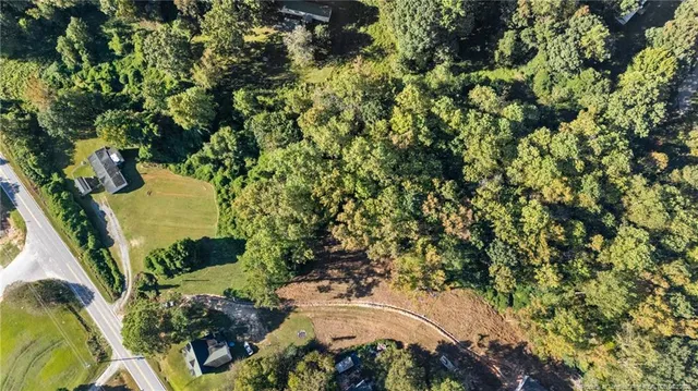 an aerial view of residential house with outdoor space and trees all around
