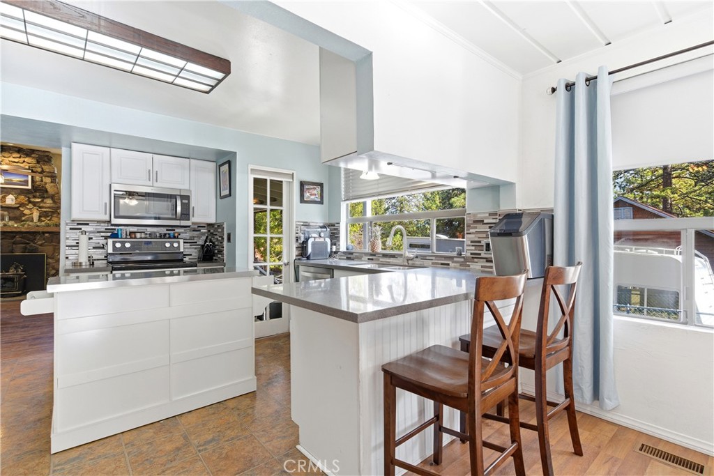 5652 Sycamore Street Wrightwood, CA 92397 - Photo 32 of 50 a kitchen with stainless steel appliances granite countertop a stove top oven a refrigerator a sink and white cabinets