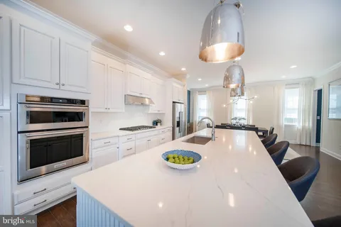 a kitchen with stainless steel appliances a dining table chairs stove refrigerator and cabinets