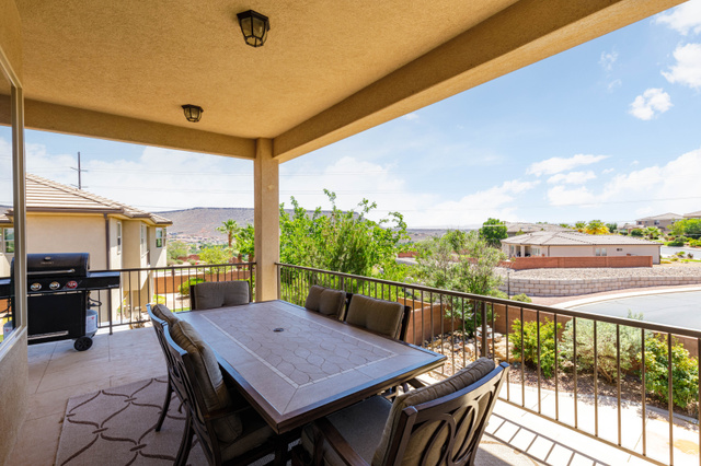 2005 West 450 S Circle St. George, UT 84770 - Photo 12 of 57 Spacious covered patio featuring a textured ceiling with two surface-mounted light fixtures, a wrought iron railing, and a tile floor