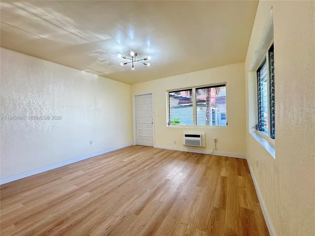 a view of an empty room with a window and wooden floor