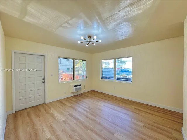 an empty room with windows and chandelier fan