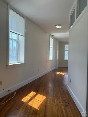 a view of empty room with window and wooden floor