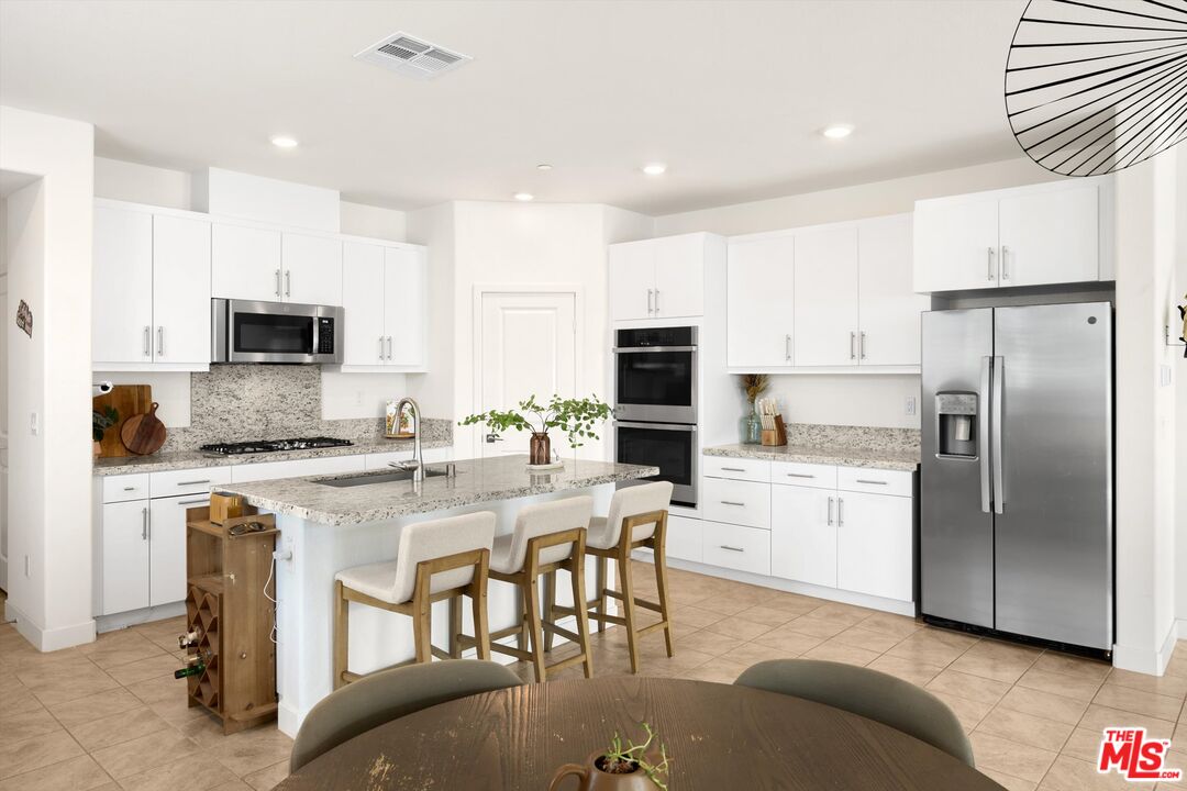 519 Tucker Avenue Rialto, CA 92377 - Photo 11 of 45 a kitchen with a refrigerator a stove top oven a sink and white cabinets