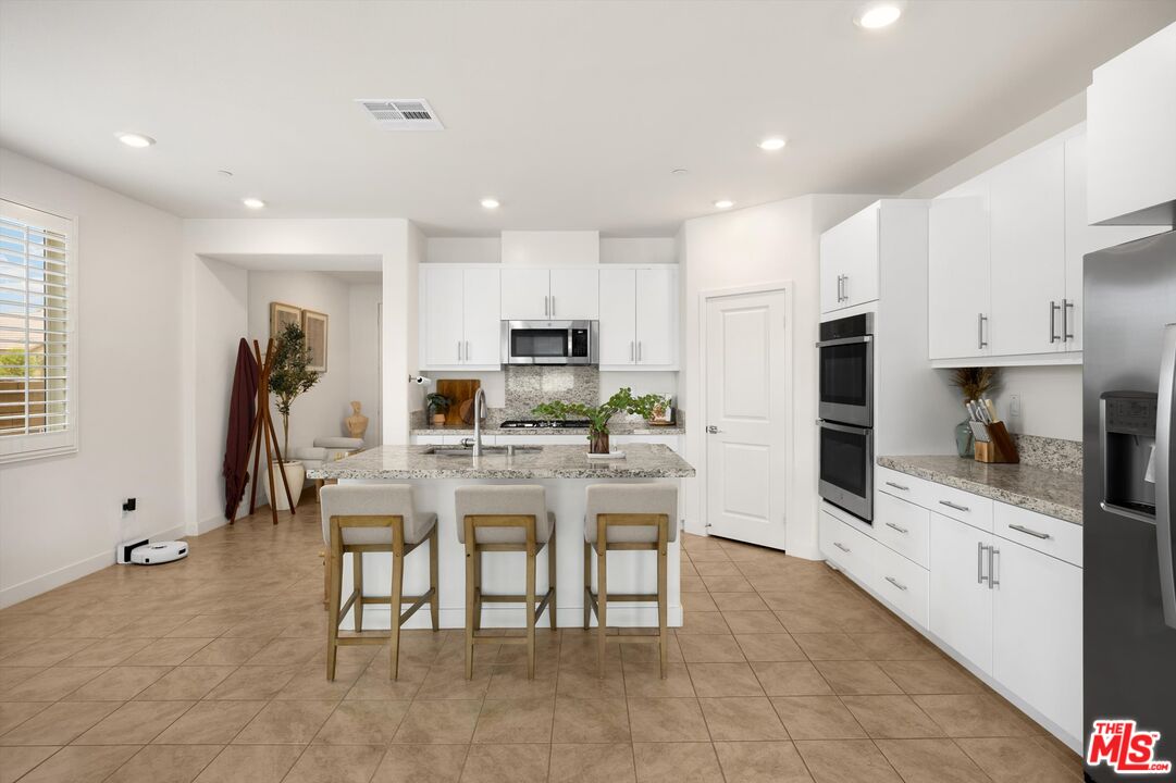 519 Tucker Avenue Rialto, CA 92377 - Photo 10 of 45 a kitchen with stainless steel appliances kitchen island granite countertop a table and chairs in it