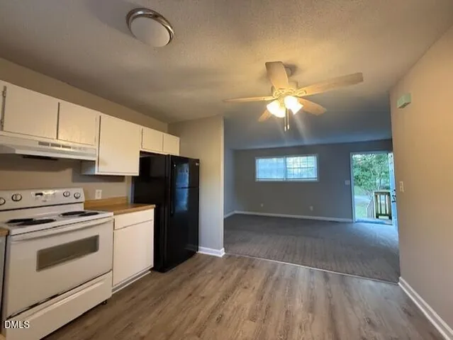 a kitchen with cabinets wooden floor and a stove top oven