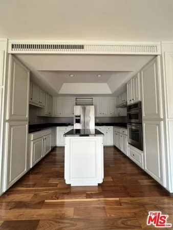 a kitchen with kitchen island stainless steel appliances a sink cabinets and wooden floor