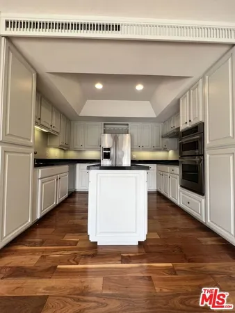 a kitchen with kitchen island granite countertop a stove top oven a sink and cabinets