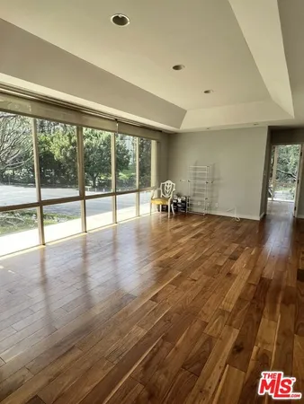 a view of empty room with wooden floor and floor to ceiling window