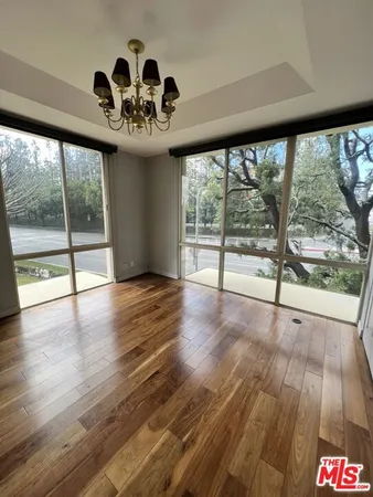 a view of an empty room with wooden floor and a large window